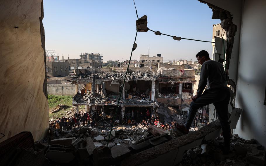 Palestinian residents and emergency services members inspect the site of the Zorob family home, which was hit overnight in Rafah in December.