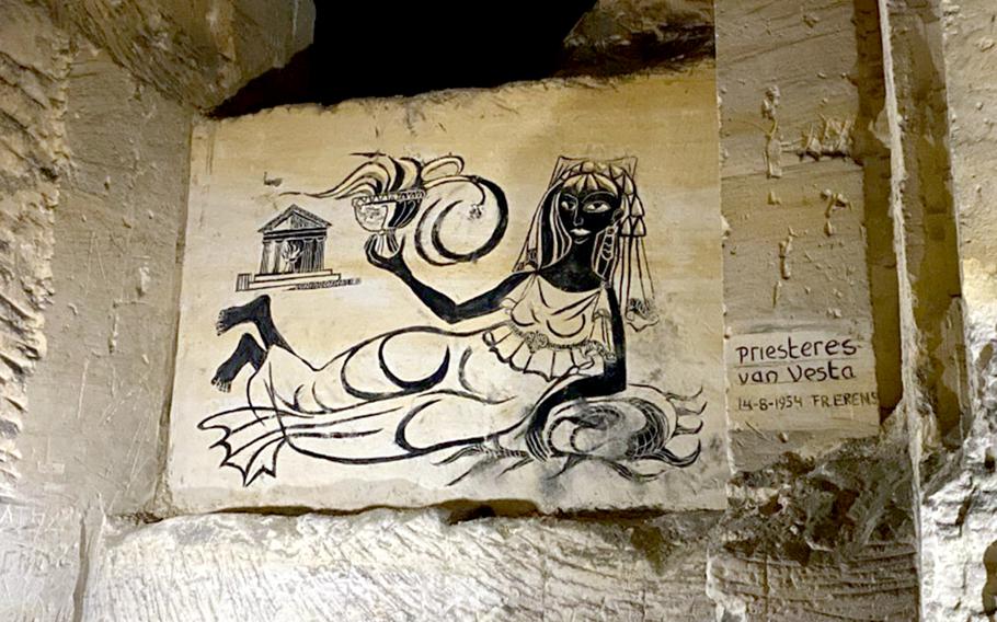 A charcoal painting of the Priestess of Vesta, Feb. 27, 2023 in the Noord Grotten in Maastricht, Netherlands. On a nearby side wall is a warning about light and fire in the tunnels.
