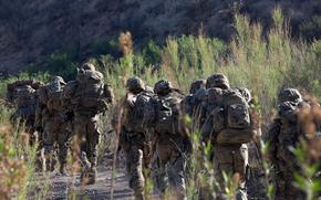 Soldiers march along a desert path.