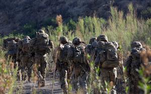 Soldiers march along a desert path.