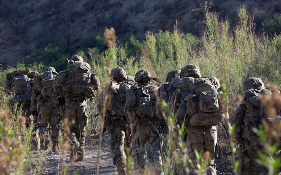 Soldiers march along a desert path.