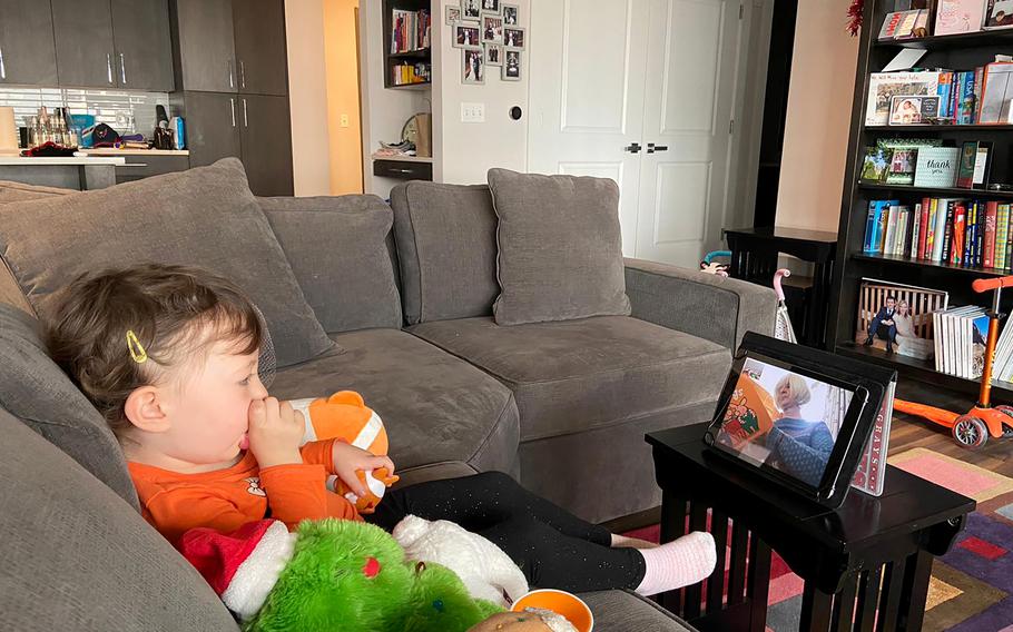 Lyla West of Arlington, Va., watches as her grandmother, Diane West, in Wimbledon, England, reads her a book over FaceTime.