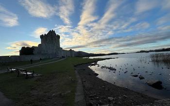 Exterior of Ross Castle on a sunny day with clouds in tky sky and a body of water on the right