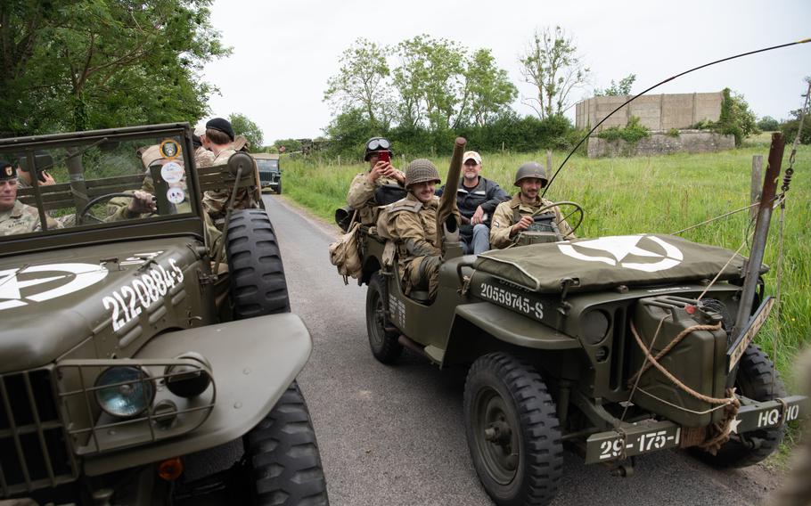 U.S. soldiers and World War II reenactors ride in vintage military vehicles.
