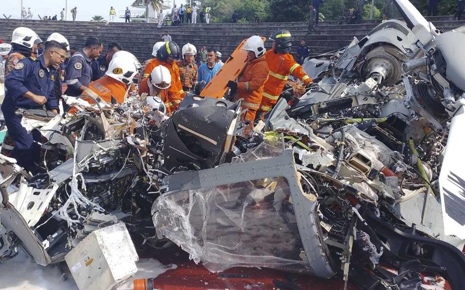 In this photo released by Fire & Rescue Department of Malaysia, fire and rescue department inspect the crash site of two helicopter in Lumur, Perak state, on April 23, 2024.