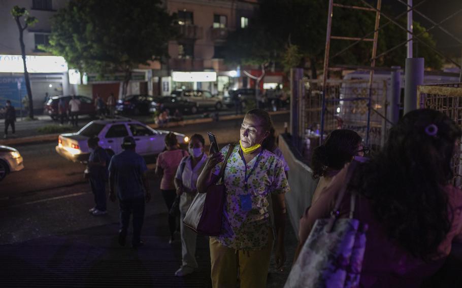Health workers check their mobile phones as they stand outside Veracruz General Hospital after a strong earthquake, in Veracruz, Mexico, Tuesday, Sept. 7, 2021. The quake struck southern Mexico near the resort of Acapulco, causing buildings to rock and sway in Mexico City nearly 200 miles away.