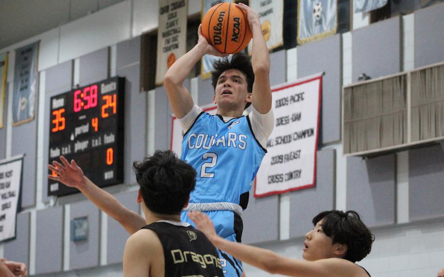 Osan's M.J. Siebert shoots over two Taejon Christian defenders during Friday's Korea boys basketball game. The Cougars won 52-31.