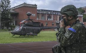 A soldier stands guard in front of a helicopter at a school during a military exercise in Hsinchu, Taiwan, on July 26, 2022. MUST CREDIT: Bloomberg photo by Lam Yik Fei.