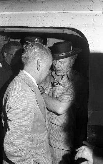 Two men in suits chat in a door frame. 