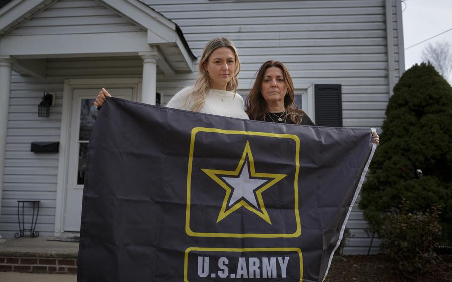 Sharon Hartz and her daughter Morgan hold an Army flag from Hartz’s late son, Thomas Anastasio, outside their home in Paramus, N.J. Anastasio died in 2019. 