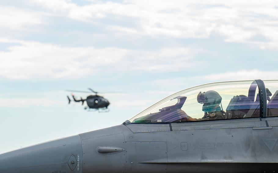 A plane with a helicopter in the background.