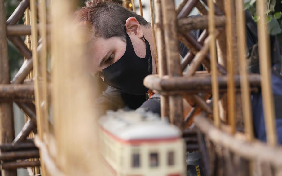 Kieran Beam works on train tracks on a bridge as part of the preparations for the annual Holiday Train Show at the New York Botanical Garden in New York, Thursday, Nov. 11, 2021. The show, which opens to the public next weekend, features model trains running through and around New York landmarks, recreated in miniature with natural materials.