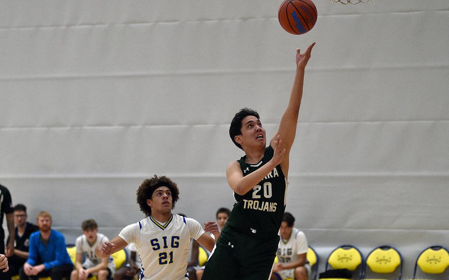 Ankara sophomore Batulla Rakhmetulla lays in a shot as Sigonella senior Jay Reed watches during pool-play action of the DODEA European basketball championships on Feb. 14, 2024, at the Wiesbaden Sports and Fitness Center on Clay Kaserne in Wiesbaden, Germany.