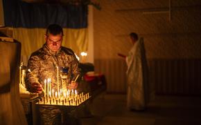 An Ukrainian serviceman of the 72nd Separate Mechanized Brigade, lights candles during a Christian Orthodox Easter religious service, in Donetsk region, Ukraine, Saturday, May 4, 2024. (AP Photo/Francisco Seco)