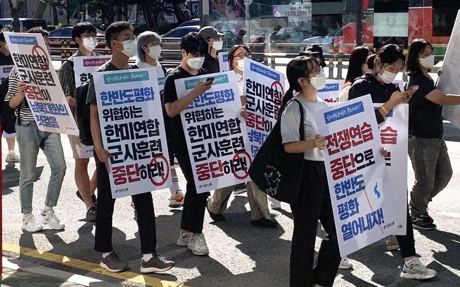 Protesters carry signs calling for peace and an end to joint military drills as they march toward the War Memorial Hall of Korea and the country's presidential office in Seoul, South Korea, Aug. 27, 2022.