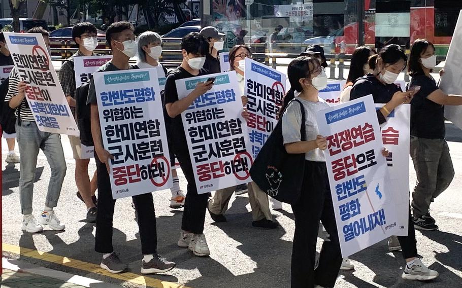 Protesters carry signs calling for peace and an end to joint military drills as they march toward the War Memorial Hall of Korea and the country's presidential office in Seoul, South Korea, Aug. 27, 2022.