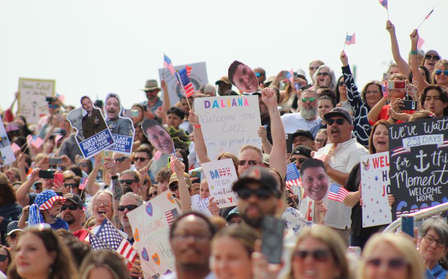 A crowd of people hold American flags and banners