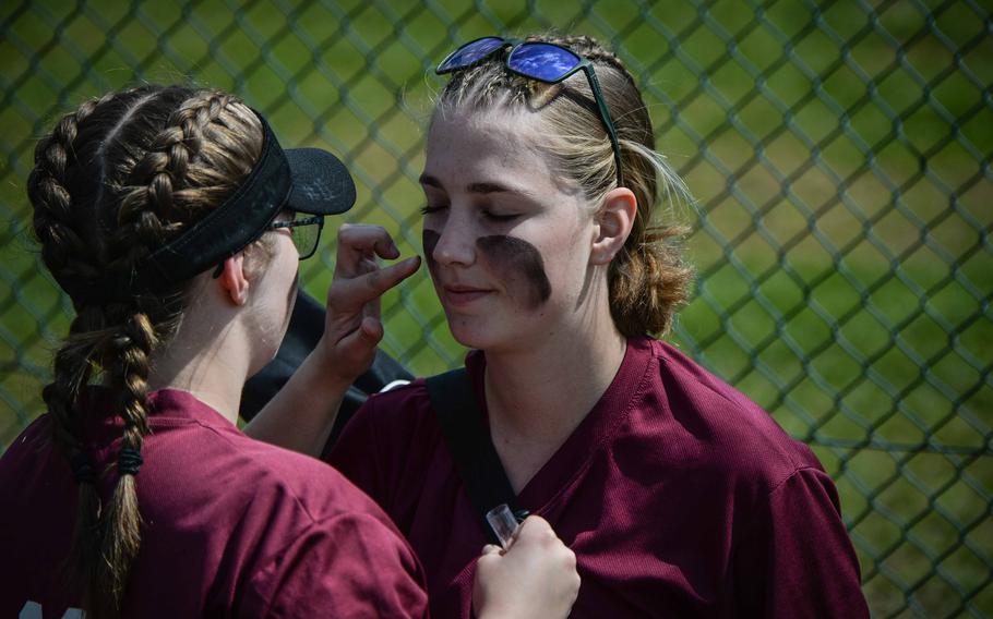 Vilseck’s Morgan Robbins applies facepaint to her teammate Kaila Haynes in the dugout before their game against Lakenheath at the DODEA-Europe Softball Championships in Kaiserslautern, Germany, May 18, 2023.