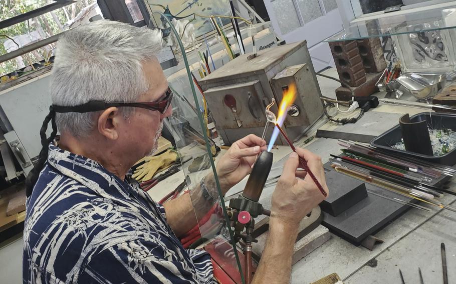 A man shapes molten glass into a figurine. 