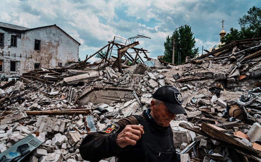 A security guard walks by the rubble of a police station that was destroyed by bombardment, in Lysychansk, Ukraine, Monday June 13, 2022. 