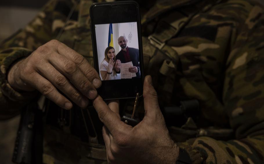 Sgt. Volodymyr Ruysn shows a wedding photo on his cellphone. He and his girlfriend were wed on the day Russia invaded Ukraine, so it was their anniversary, too.