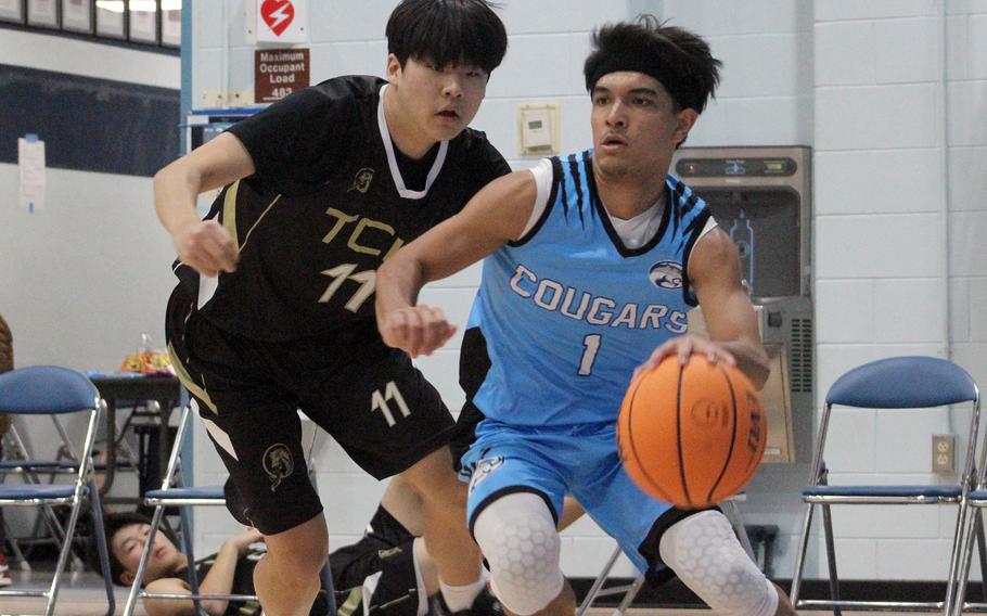 Osan's Jayden Hightower dribbles against Taejon Christian's Woosung Chong during Friday's Korea boys basketball game. The Cougars won 52-31.