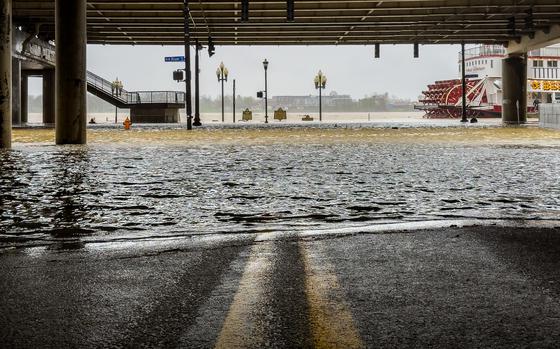 Water floods over the banks of the Ohio River as a riverboat paddles past.