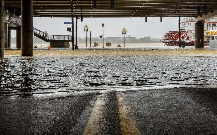 Water floods over the banks of the Ohio River as a riverboat paddles past.