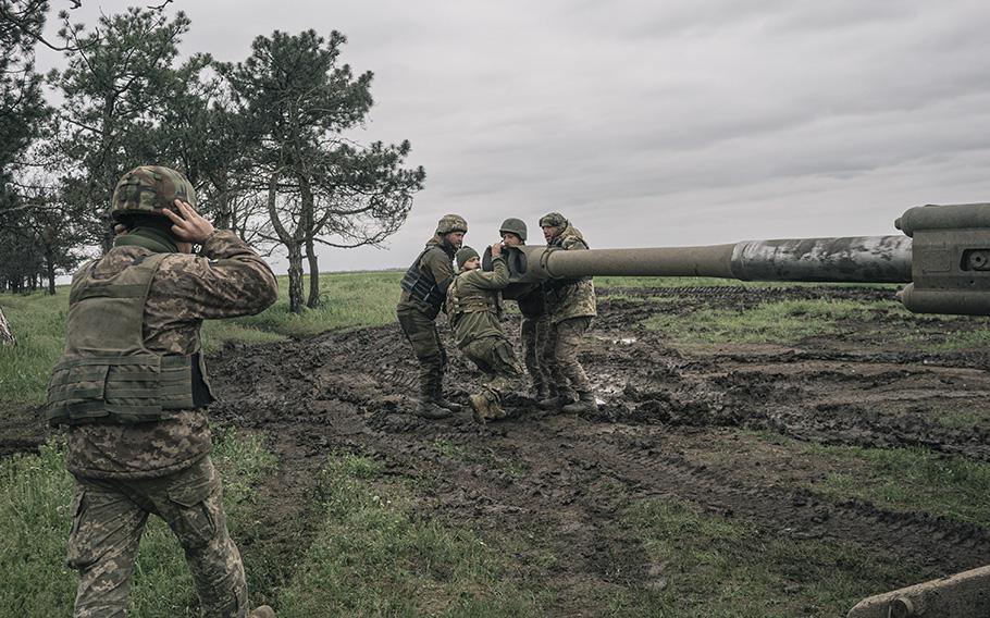 Members of the 406th Separate Artillery Brigade adjust the position of a howitzer. 