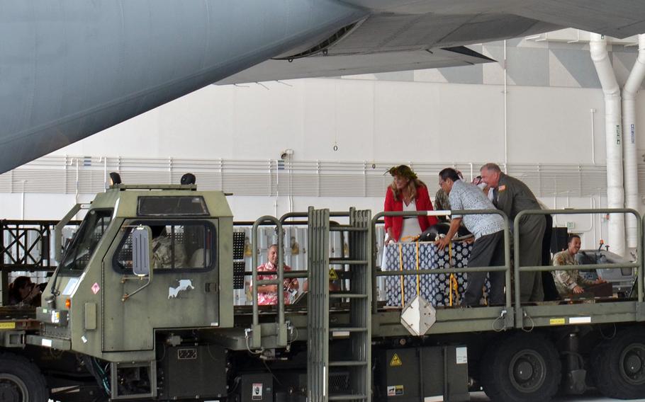 U.S. Ambassador to the Federated States of Micronesia Jennifer Johnson, left, President of the Federated States of Micronesia Wesley Simina, center, and U.S. Forces Japan commander Lt. Gen. Ricky Rupp push an Operation Christmas Drop bundle onto a C-130J Super Hercules at Andersen Air Force Base, Guam, Monday, Dec. 4, 2023.