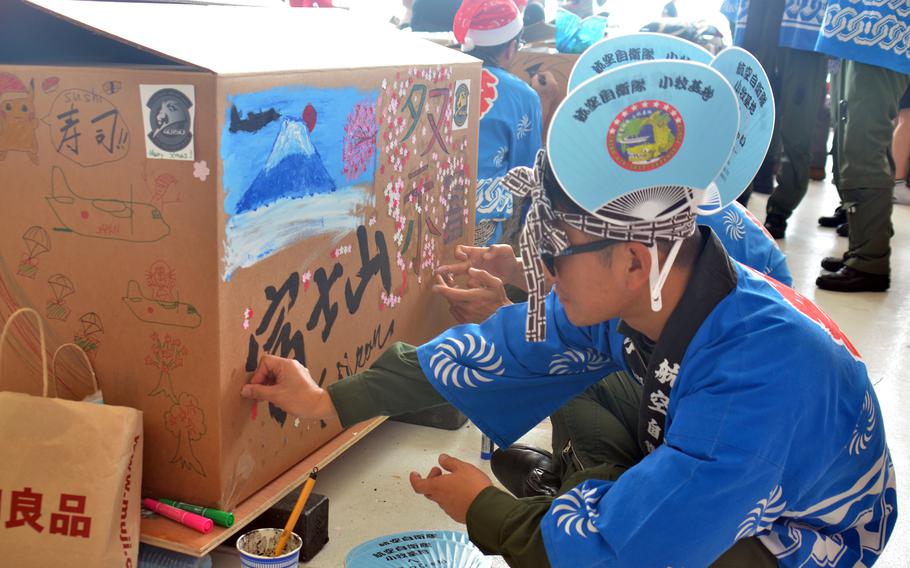 A Japanese airman decorates an Operation Christmas Drop bundle at Andersen Air Force Base, Guam, Saturday, Dec. 2, 2023. 