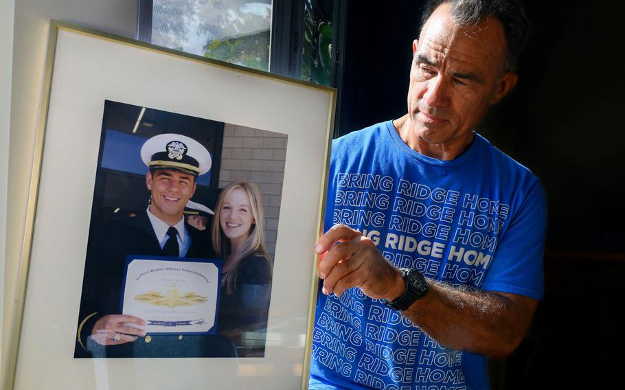 Derek Alkonis holds a picture of his son, U.S. Navy Lt. Ridge Alkonis, and his son’s wife, Brittany Alkonis, in Dana Point, Calif., on Monday, Sept. 12, 2022. Lt. Alkonis is serving a 3-year prison sentence in Japan after being in a traffic accident that killed two people. His family says he suffered mountain sickness and became unconscious before the crash.