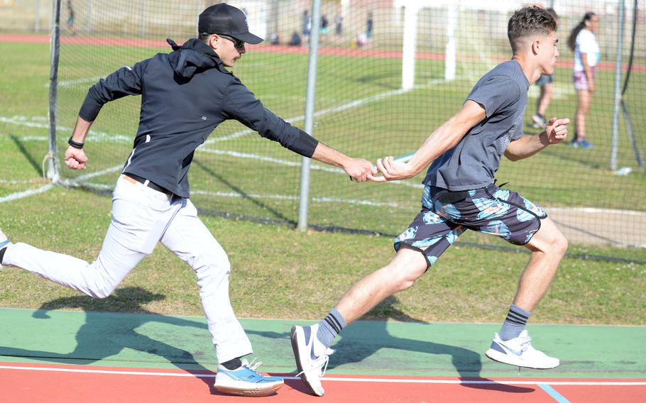 Kubasaki distance-relay coach Gable Schmidt hands off the baton to sophomore Ian Lyons.