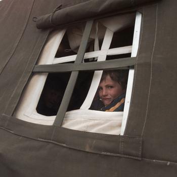 A couple of refugee children peer out the window of their classroom at the Radusa refugee camp in Macedonia, April 22, 1999.