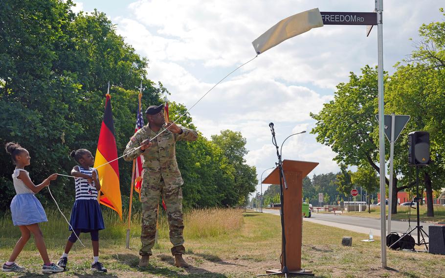 U.S. Army Garrison Bavaria commander Col. Kevin A. Poole and two of the youngest audience members at the street dedication ceremony, June 14, 2023, reveal the new street sign at Tower Barracks, Grafenwoehr, Germany. Freedom Road commemorates the end of slavery in America.