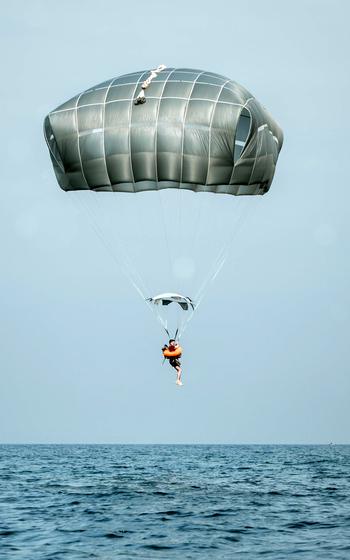 A single paratrooper is seen gliding into a body of water.