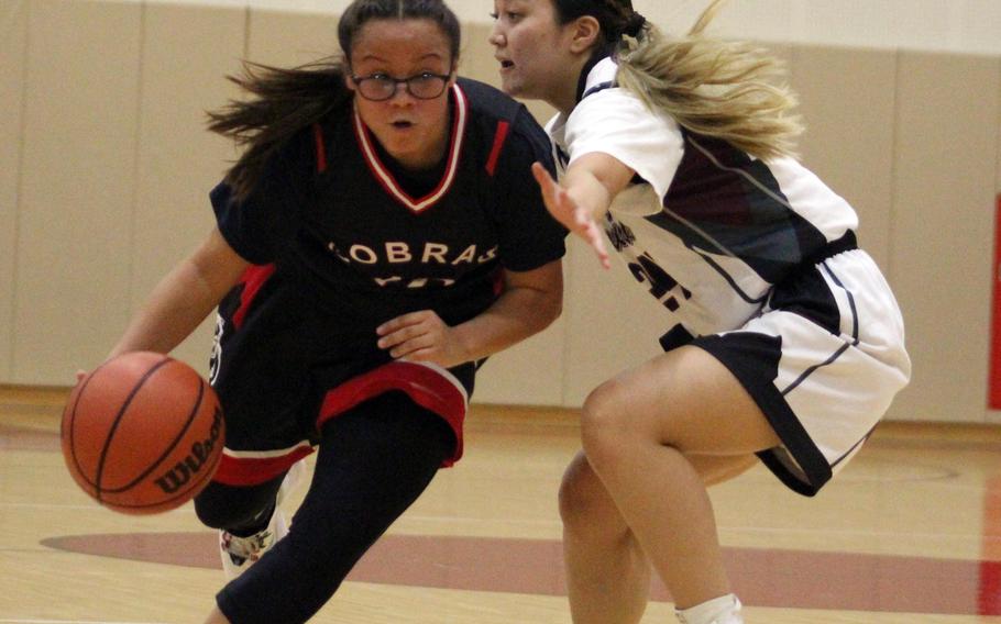 E.J. King's Angela Romero drives around Matthew C. Perry's Towa Albsmeyer during Friday's DODEA-Japan basketball game. The Cobras won 49-13.