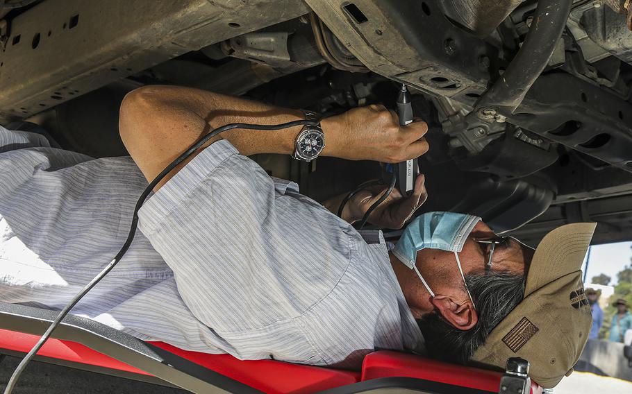 An LAPD detective etches vehicle identification numbers onto a car’s catalytic converter as a preventative measure against theft on April 6, 2022, in Los Angeles. 