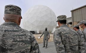 Service members stand near the front of a white dome structure.