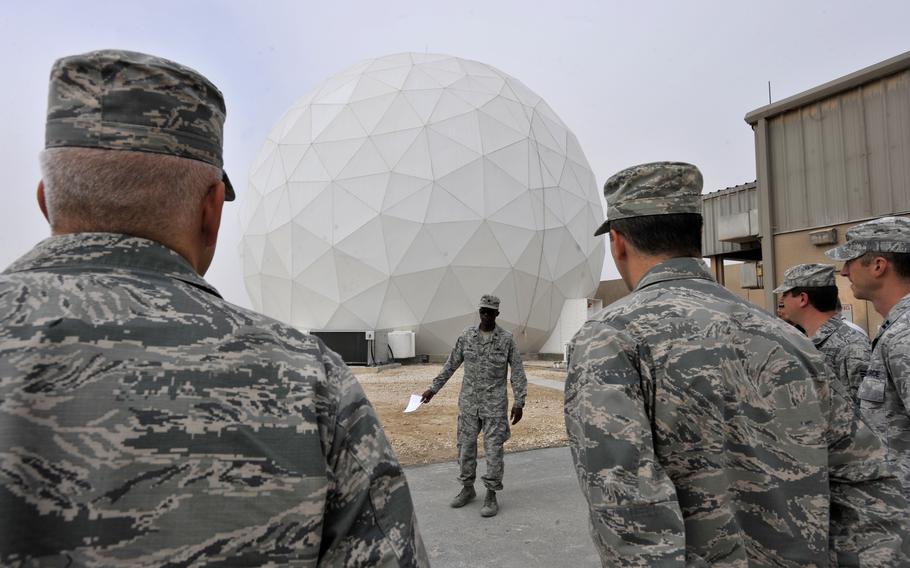 Service members stand near the front of a white dome structure.