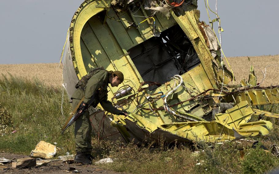 A pro-Russian rebel touches the MH17 wreckage.