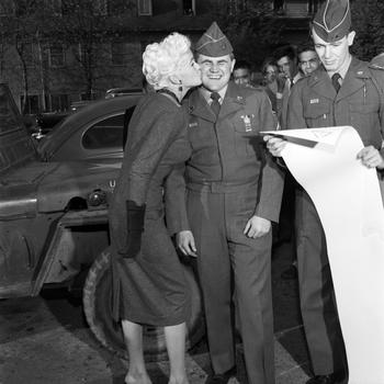 A servicemember collects his prize — a kiss on the cheek from Jayne Mansfield — after winning a contest, Oct. 5, 1957. Photographer Red Grandy identified him only by the last name Zandarski on the back of the contact sheet. The service member holding the scroll was identified as Watkins. 