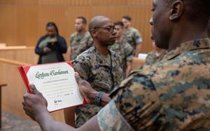 U.S. Marine Corps Staff Sgt. Marcellous Dixon reenlists in the courtroom of Camp Blaz, Guam, Dec. 27, 2024. Marines receiving bonuses for reenlisting this year will have to wait until next fiscal year to receive their incentive payment, which will be issued on a funding-available basis, according to a recent service message.