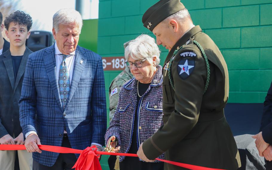 Joanne Showman uses scissors to cut a ribbon as  Thomas Lombardo III and Maj. Gen. Charles Lombardo look on.