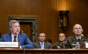 Daniel Driscoll, left, seated at a table and speaking with Gen. Randy George sitting next to him.