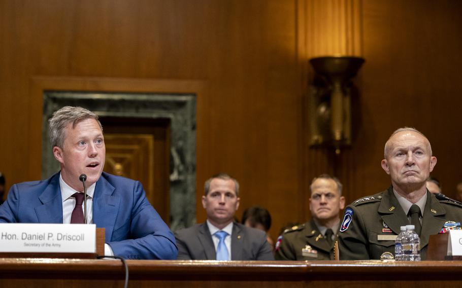 Daniel Driscoll, left, seated at a table and speaking with Gen. Randy George sitting next to him.