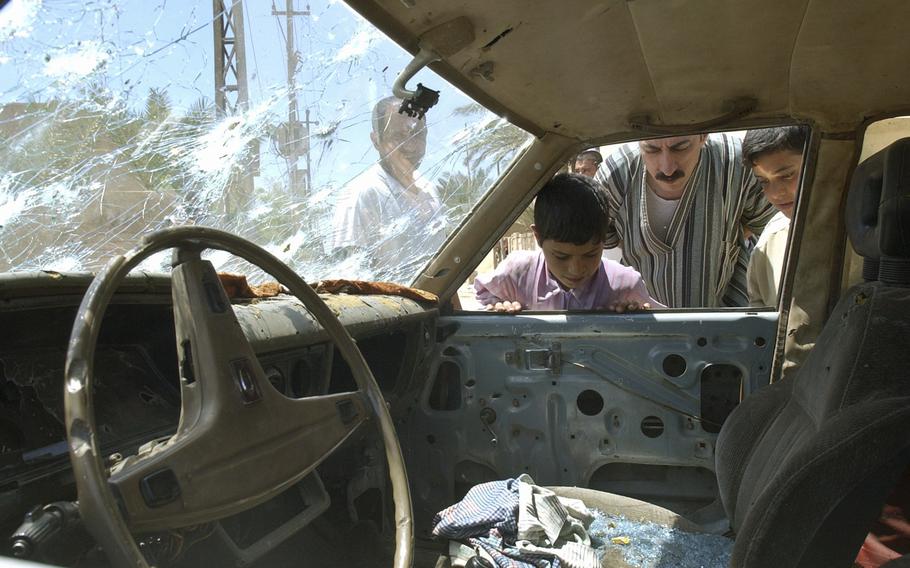 In this April 29, 2003, file photo, residents of Fallujah, Iraq, look into a bullet-riddled car outside a school where U.S. soldiers fired on demonstrators the night before.