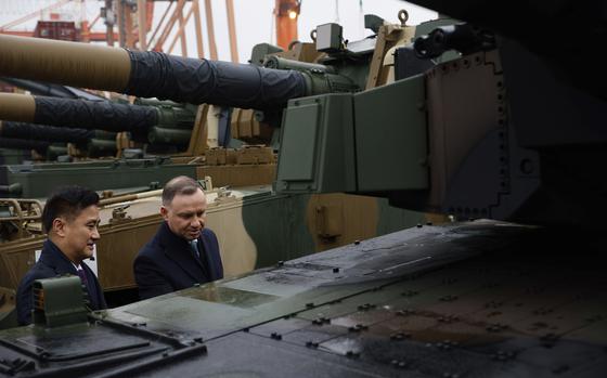 South Korea's Defense Acquisition Program Administration Minister Eom Dong-hwan, left, and Polish President Andrzej Duda, right, inspects the South Korean Black Panther K2 tank in the Polish Navy port of Gdynia, Poland, Tuesday, Dec. 6, 2022. Poland's President Andrzej Duda and the defense minister on Tuesday welcomed the first delivery of tanks and howitzers from South Korea, hailing the swift implementation of a deal signed in the summer in the face of the war in neighbouring Ukraine. (AP Photo/Michal Dyjuk)