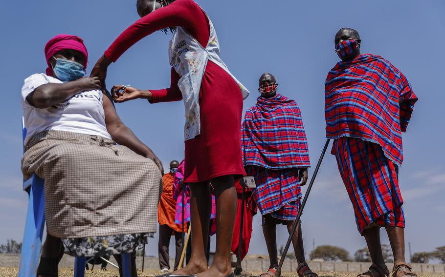 Maasai men line up to receive the AstraZeneca coronavirus vaccine look over as a woman, who is not Maasai. receives a jab at a clinic in Kimana, southern Kenya Saturday, Aug. 28, 2021. Plans for COVID-19 booster shots in some Western countries are highlighting vast disparities in access to vaccines around the world.