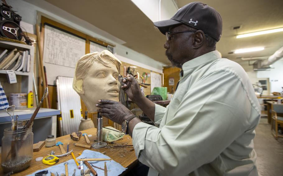 In his studio in Lubbock, Texas., Eddie Dixon demonstrates how he adds details to the eyes of a sculpture. He designed a Buffalo Soldier for the U.S. Military Academy. 